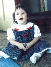 A little girl sitting on the floor in front of a fireplace.