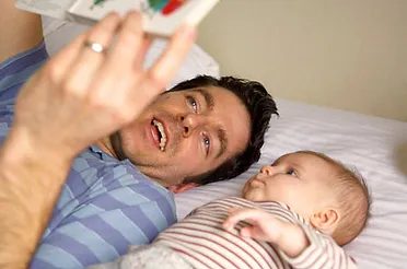 A man and baby laying on the bed