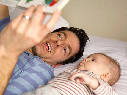 A man and baby laying on the bed