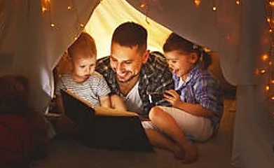 A man and two children are reading a book.