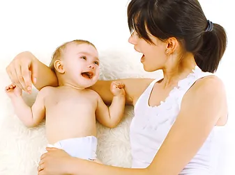 A woman is holding a baby and smiling.