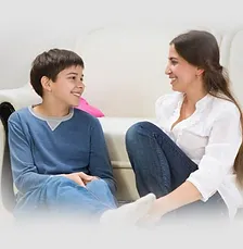 A woman and boy sitting on the couch talking.