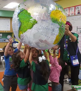 A group of children holding up an inflatable globe.