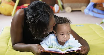 A woman reading to a child on the floor