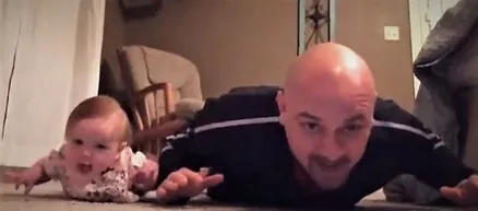 A bald man laying on the ground in front of a chair.